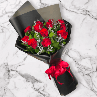 Bouquet of red roses wrapped in black paper with a red ribbon