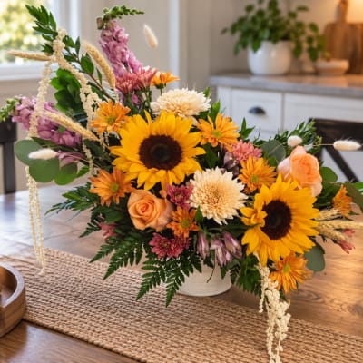 Mixed bouquet with sunflowers, orange roses, and chrysanthemums in a white vase