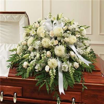 White funeral spray with lilies and roses on a casket