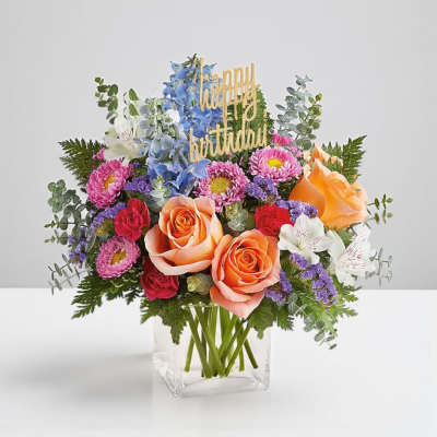 Mixed bouquet in a clear vase with a "happy birthday" topper