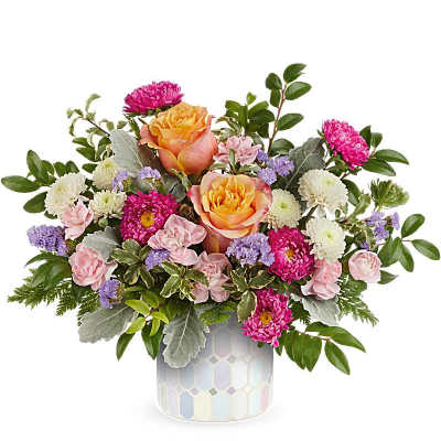 Mixed bouquet of pink and peach flowers in a patterned vase