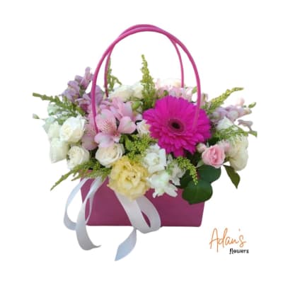 Pink basket arrangement with mixed pastel flowers and a ribbon bow