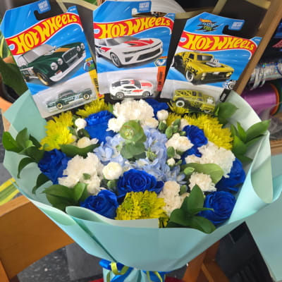 Bouquet of blue, white, and yellow flowers with three Hot Wheels toy cars