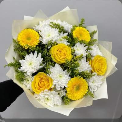 Bouquet of yellow roses and white daisies wrapped in pale paper