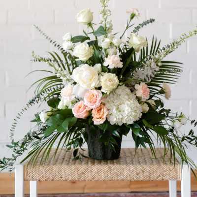 White and blush floral arrangement in a black vase