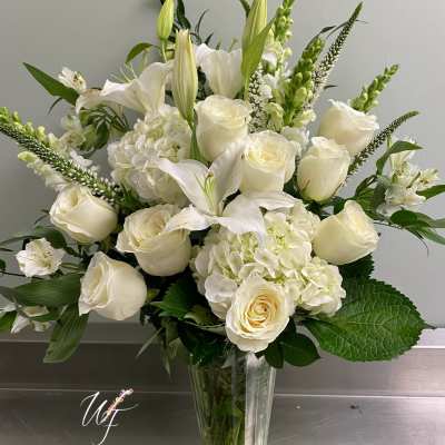 White roses and lilies arranged in a clear glass vase