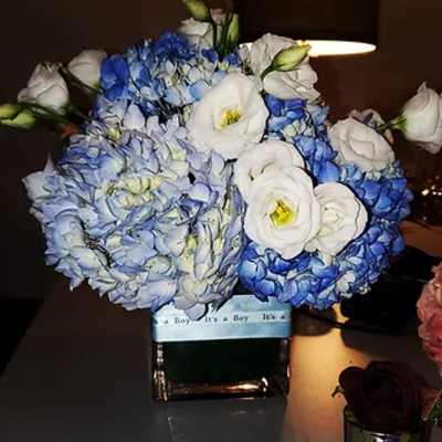 Blue and white flower arrangement in a square vase with a baby boy ribbon