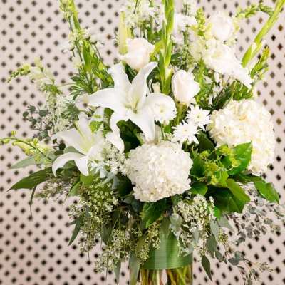 White lilies and hydrangeas in a clear glass vase
