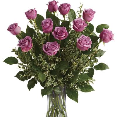 Pink roses arranged in a clear glass vase with mixed greenery