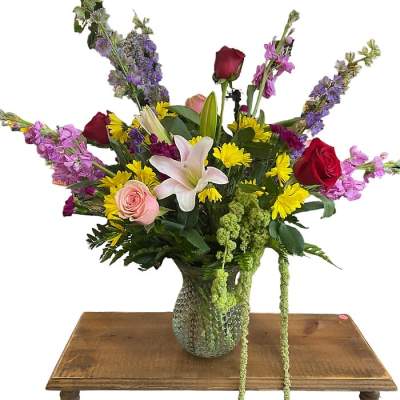 Mixed bouquet with roses, lilies, and yellow daisies in a glass vase