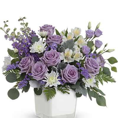 Lavender roses and white flowers in a clear square vase