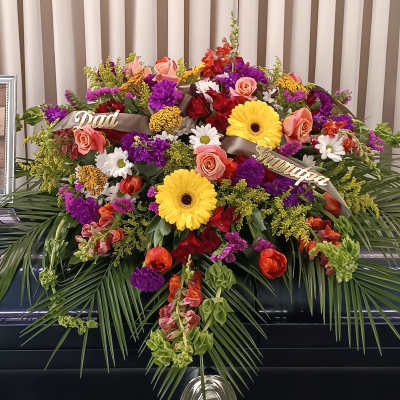 Large funeral spray with mixed flowers and ribbons on a stand