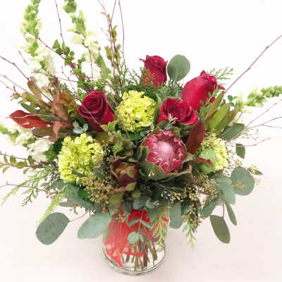 Bouquet of red roses and green blooms in a glass vase