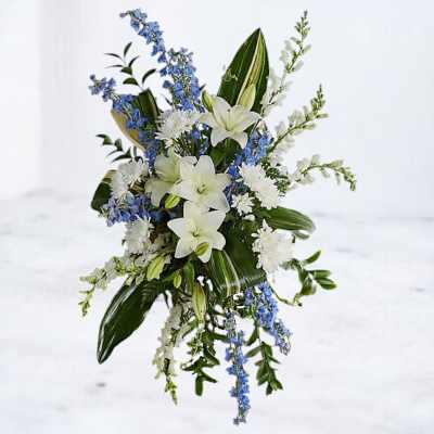 White lilies with blue and white flowers in a cascading arrangement