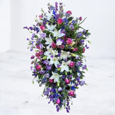 Tall cascading arrangement of white lilies with pink and purple blooms in a teardrop shape