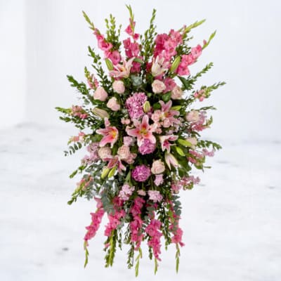 Tall pink spray arrangement with lilies, carnations, roses, and other blooms.