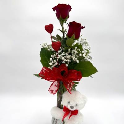 Red roses in a vase with a teddy bear and heart decorations