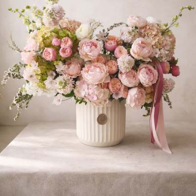 Large pastel bouquet of pink and white flowers in a ribbed white vase
