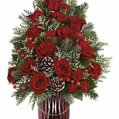 Red roses and pinecones arranged in a red glass vase