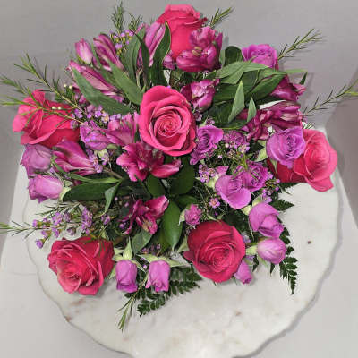Pink and purple rose bouquet on a white round base
