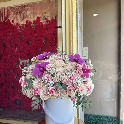 Large pink rose arrangement in a white hatbox with purple orchids