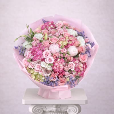 Large bouquet of pink roses and mixed blooms wrapped in pink paper