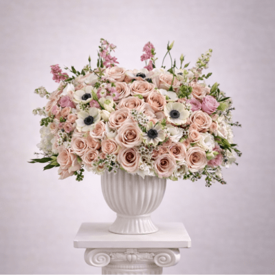 Blush and white rose arrangement in a white urn vase