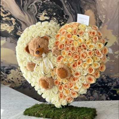 Heart-shaped rose arrangement with two teddy bears on a moss base