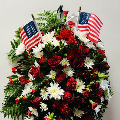 Red and white floral standing wreath with two American flags