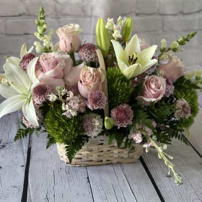 Pink roses and white lilies arranged in a wicker basket