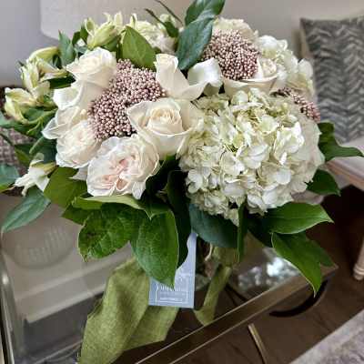 Bouquet of white roses, hydrangeas, and pale pink berries with green leaves