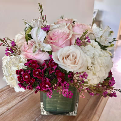 Pink and white roses arranged in a square glass vase