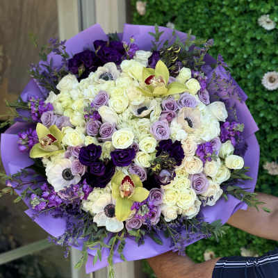 Bouquet of white, lavender, and deep purple flowers wrapped in purple paper