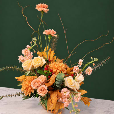 Autumn floral arrangement with peach roses, orange mums, and pink carnations in a vase