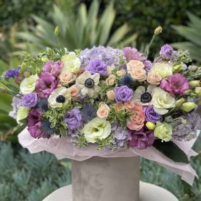 Pastel bouquet of roses, lisianthus, hydrangeas, and anemones in a hatbox