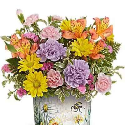 Colorful mixed flower arrangement in a square glass vase with bee artwork