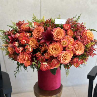Large orange and pink floral arrangement in a magenta vase