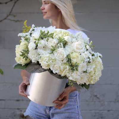 Woman holding a large white floral arrangement in a silver box