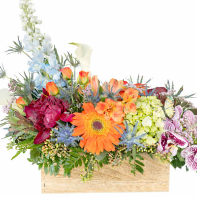Mixed floral arrangement in a wooden box with orange, blue, and pink blooms