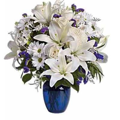 White lilies and daisies in a blue glass vase