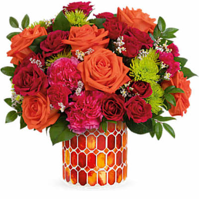 Orange and red rose bouquet in a patterned glass vase