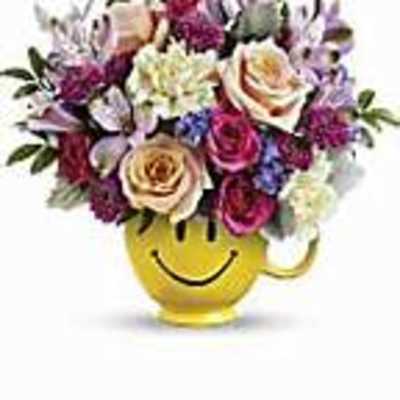 Mixed flower bouquet in a yellow smiley-face mug