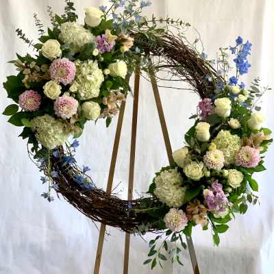 Large floral wreath with white, pink, and blue flowers on a wooden stand