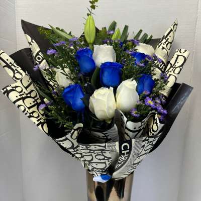 Bouquet of blue and white roses in a tall metallic vase