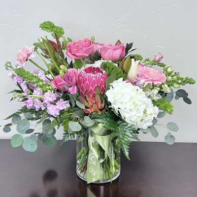 Pink and white mixed bouquet in a glass vase with a green ribbon
