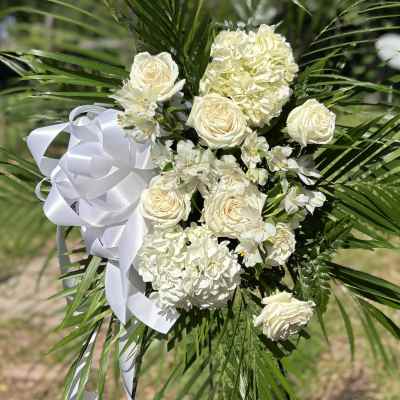 White floral standing spray with roses, hydrangeas, and ribbon