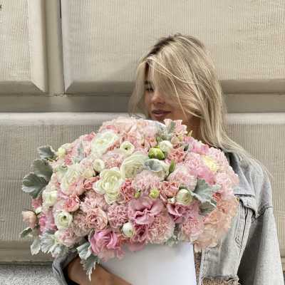 Woman holding a large pastel pink and white bouquet in a white box