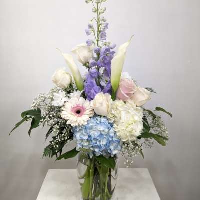 Tall pastel flower arrangement in a clear glass vase