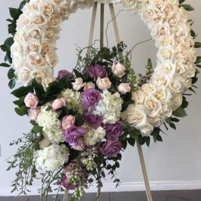 Large floral wreath of white and lavender roses on an easel