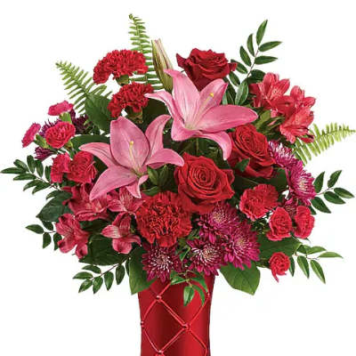 Red and pink mixed flower arrangement in a red vase